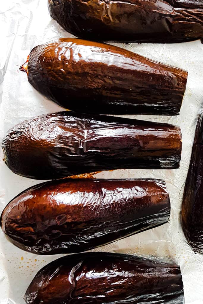 The roasted eggplant still on the pan with shriveled skin