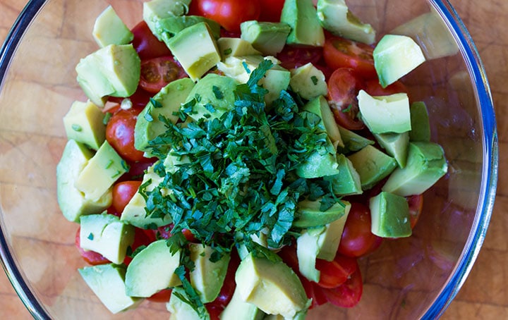 The herbs added to the salad bowl with the avocado and tomatoes 