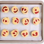 Raspberry-filled scone dough arranged on a parchment-lined baking tray, ready to go into the oven.