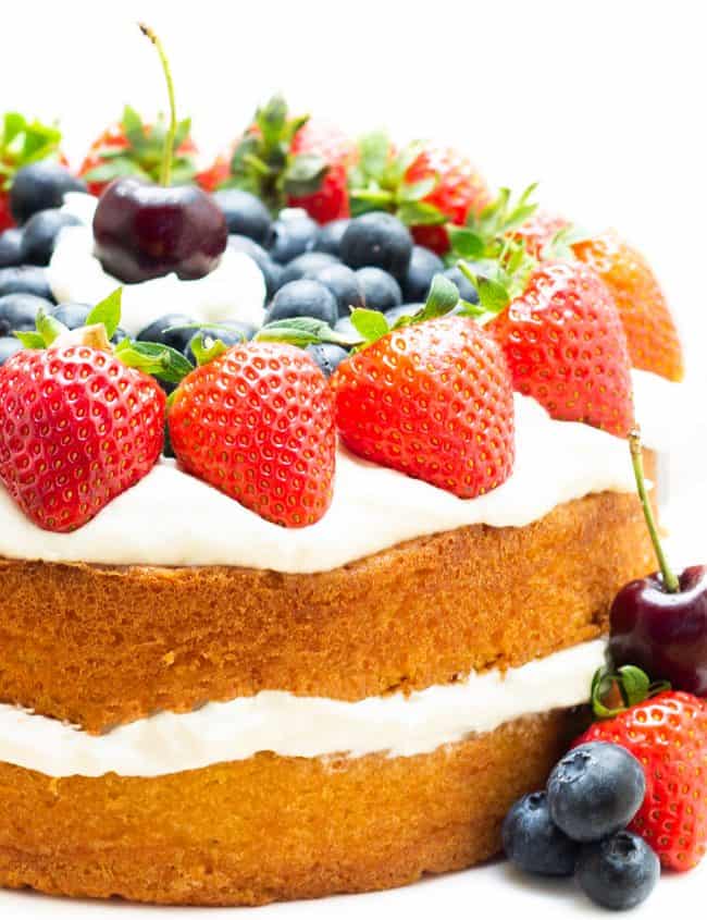 A layer cake topped with cream and fruit