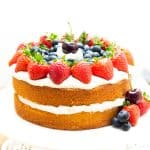 A layer cake on a cake stand topped with cream and fruit