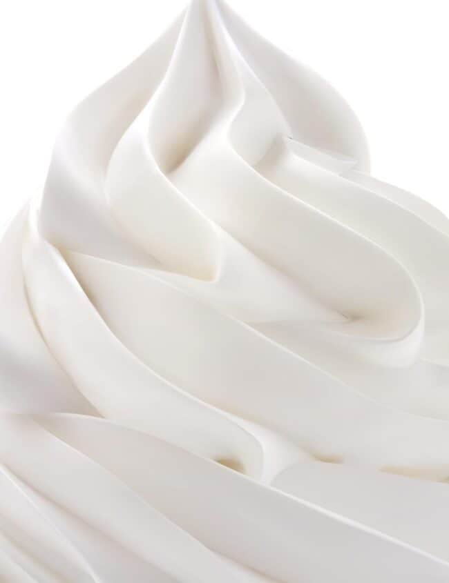 A close up of a swirl of whipped cream with a black background