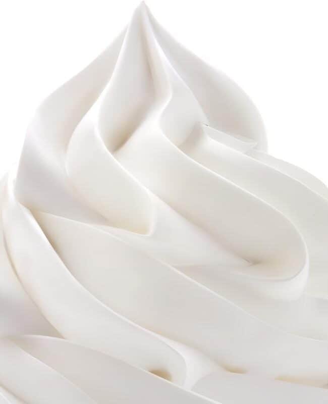 A close up of whipped cream swirled onto a surface with a white background