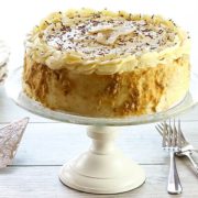 A cake on a cake plate with forks and plates on the table