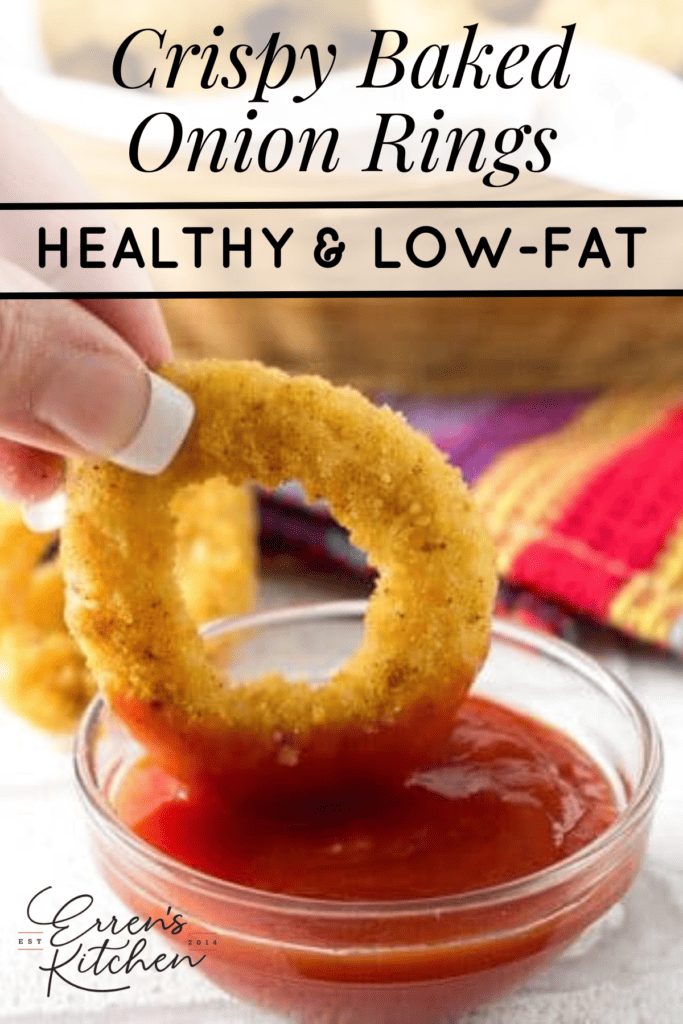 A crispy onion ring being dipped into ketchup.