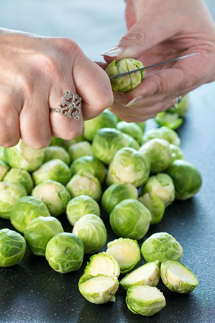 A cross being cut through the stem of a Brussels sprout
