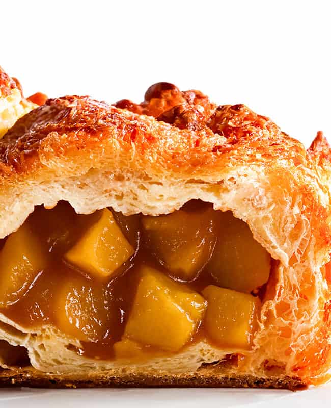 Apple Turnovers on a plate with a close up of one broken open to show the apple filling.