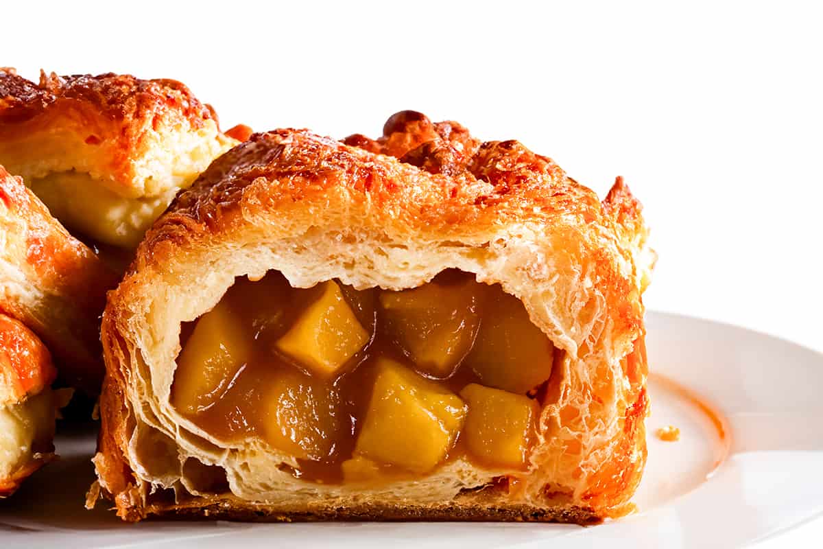 Apple Turnovers on a plate with a close up of one broken open to show the apple filling.