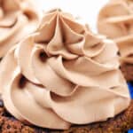 a close up of a cupcake topped with Chocolate Whipped Cream with more in the background