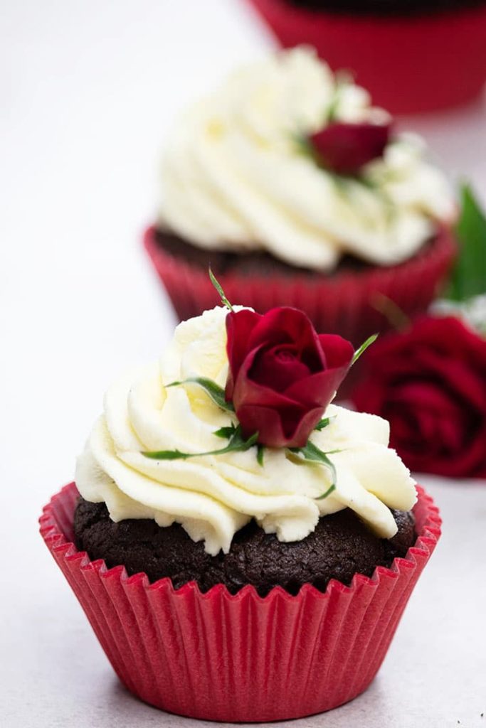 Three Easy Homemade Chocolate Cupcakes with whipped cream and baby roses for decoration