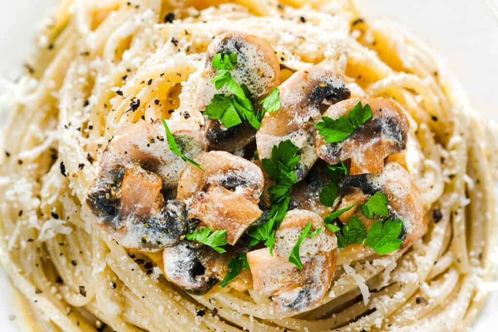 a close up image of a plate of Creamy Mushroom Spaghetti topped with mushrooms and parsley