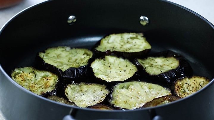 A layer of roasted eggplant slices in a pan