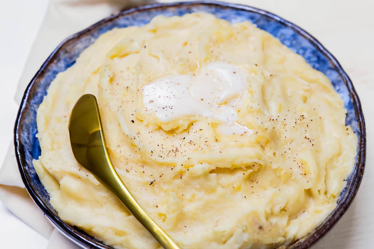 a bowl of freshly made mashed potatoes topped with butter.