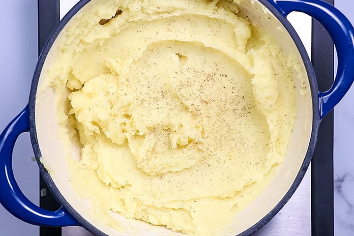 Mashed postatoes in a pot with salt and pepper