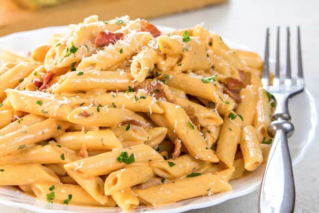 Penne Alla Vodka piled high on a white plate, sprinkled with parmasean cheese.