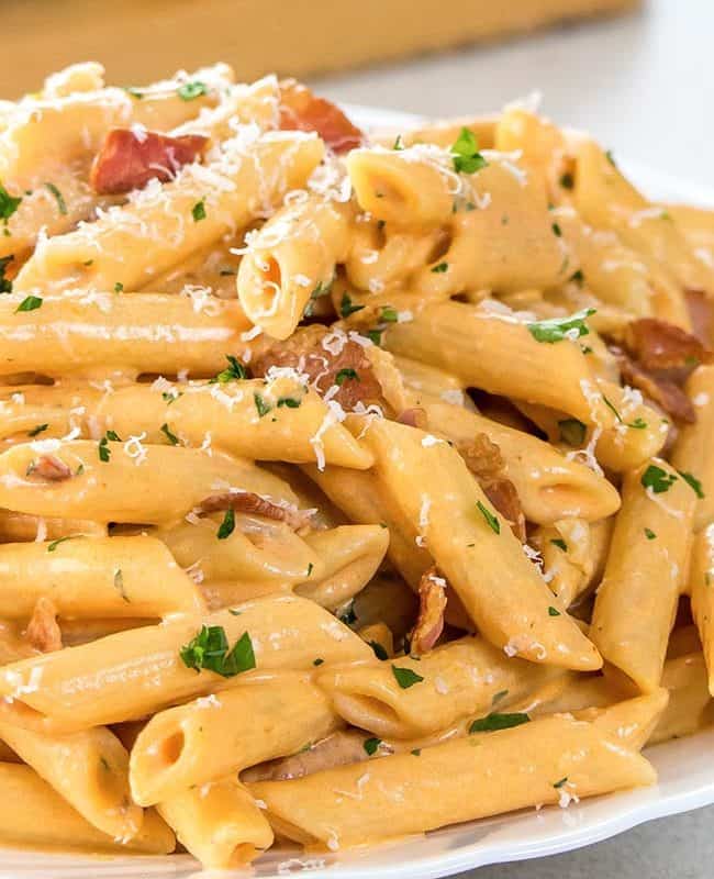 Penne Alla Vodka piled high on a white plate, sprinkled with parmasean cheese.