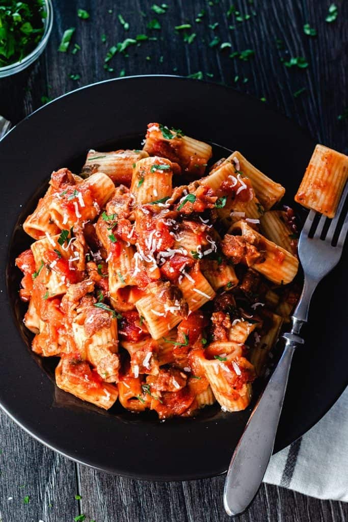 a plate of pasta with Amatriciana Sauce topped with grated cheese and parsley