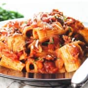 A heaping bowl of pasta with Amatriciana Sauce topped with grated cheese