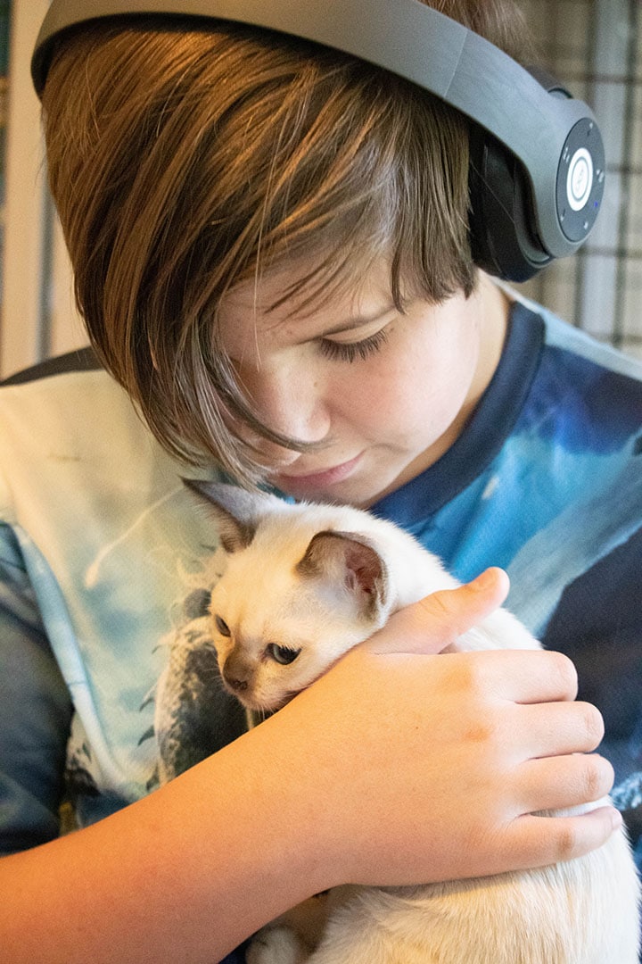 Ethan holding a little white cat with a black nose.