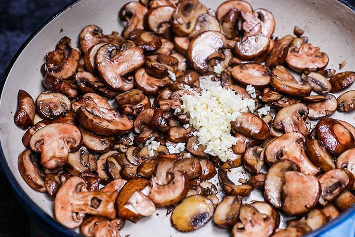 garlic added to the cooked mushrooms in the pan