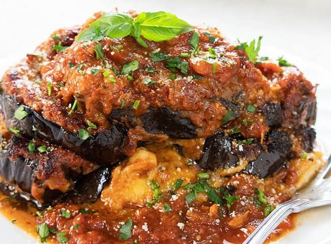 Baked Eggplant Parmesan on a plate topped with basil leaves