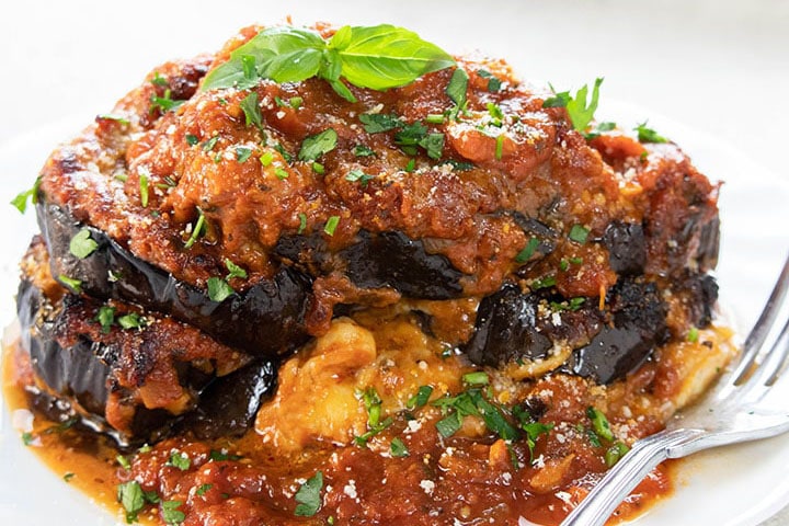 Baked Eggplant Parmesan on a plate topped with basil leaves