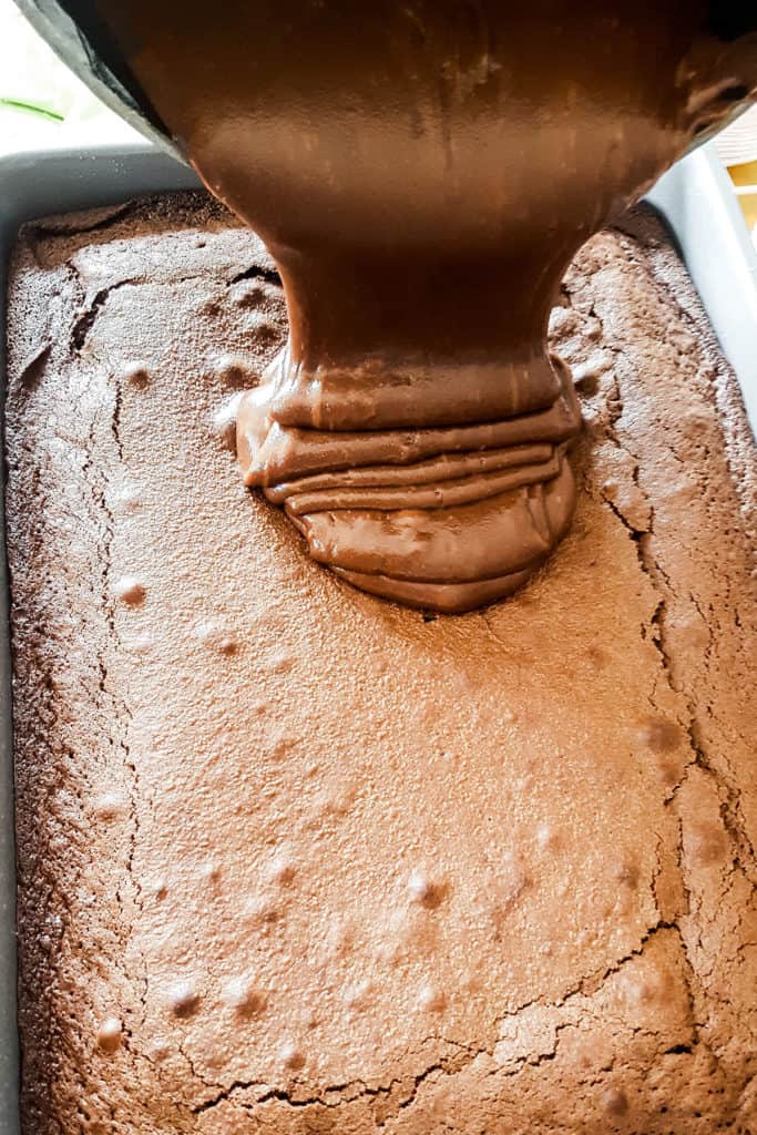 the chocolate fudge being poured onto the cake