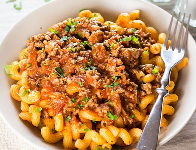 A plate of curly pasta topped high with Greek Style Meat Sauce {Makaronia Me Kima}