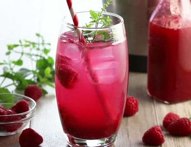 A straw and sprig of mint with ice and raspberry mojito