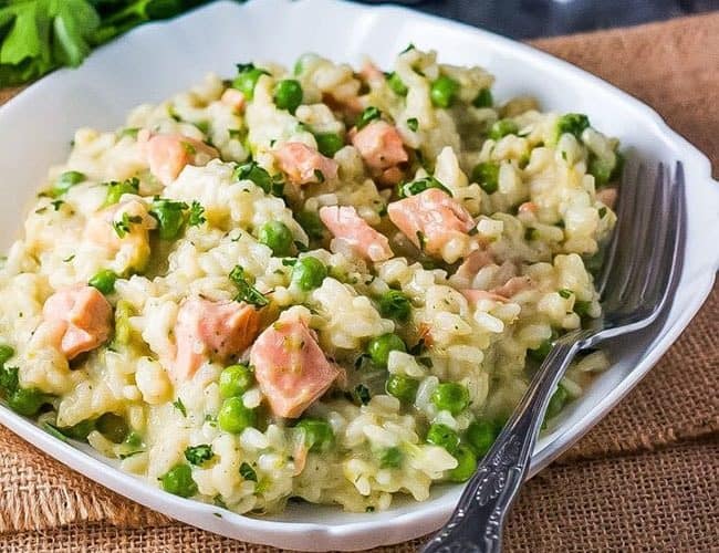 Easy Salmon and Pea Risotto on a white dish with a fork next to it.