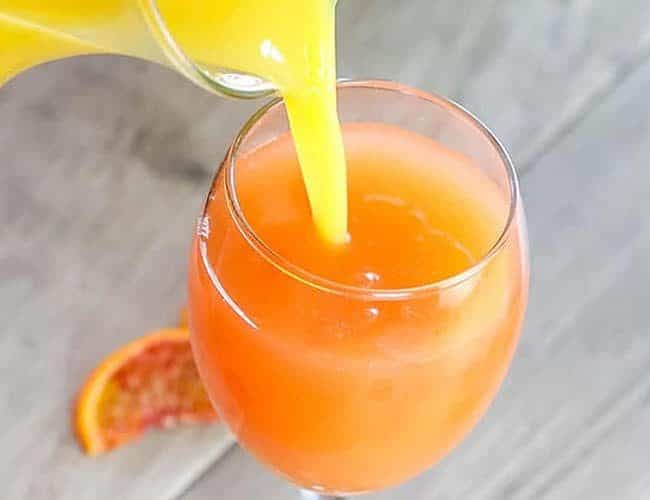 Juice being poured into a glass with The Perfect Mimosa