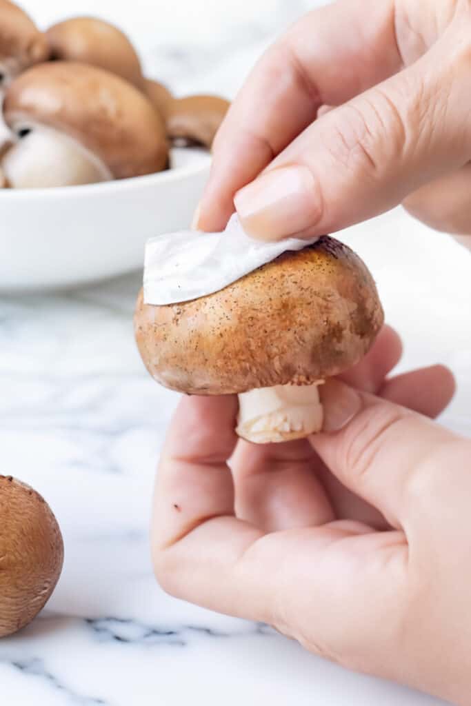 a woman's cleaning a mushroom with a paper towel. 