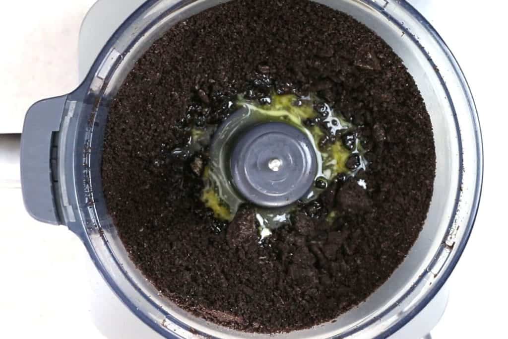 crushed oreo cookies in a food processor with melted butter