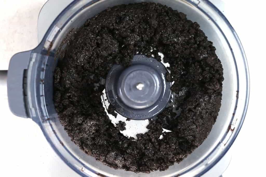 crushed oreo cookies in a food processor coated with melted butter