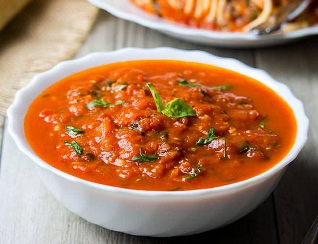 A bowl of Quick & Easy Marinara Sauce topped with fresh basil