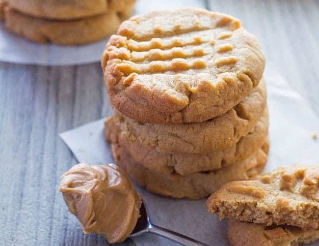 A stack of Classic Peanut Butter Cookies with a spoonful of peanut butter next to it