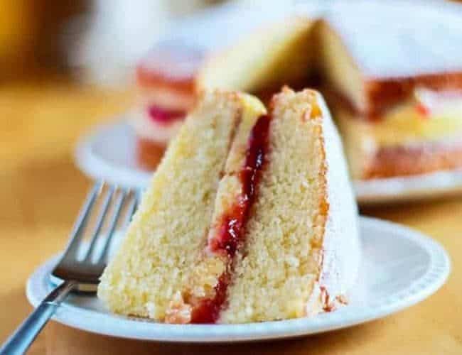 Slice of Victoria Sponge Cake filled with buttercream and raspberry jam on a plate