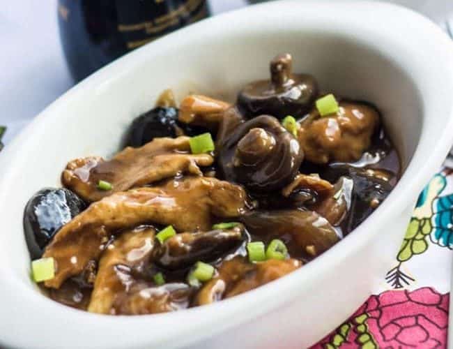 Chicken with Chinese Mushrooms in a white bowl scattered with green onion slices