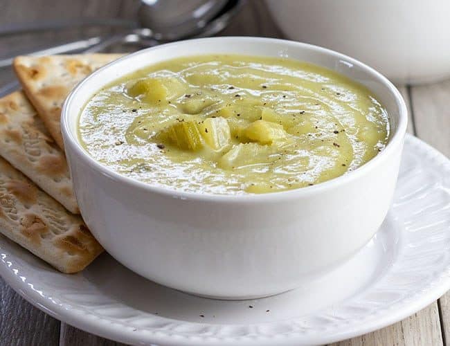 Creamy Celery Soup in a white bowl served with crackers on the side