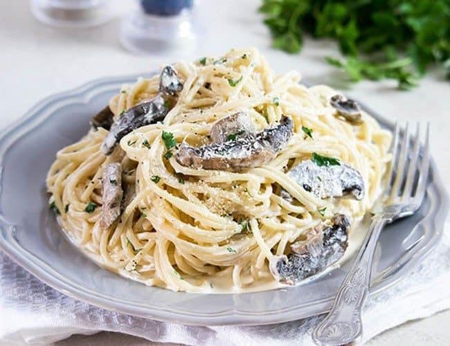 Creamy Mushroom Spaghetti on a grey plate with salt, pepper and parsley in the background