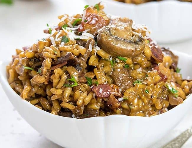 Easy Mushroom & Bacon Risotto piled high in a white bowl