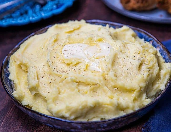 A big bowl of mashed potatoes with butter melting on top