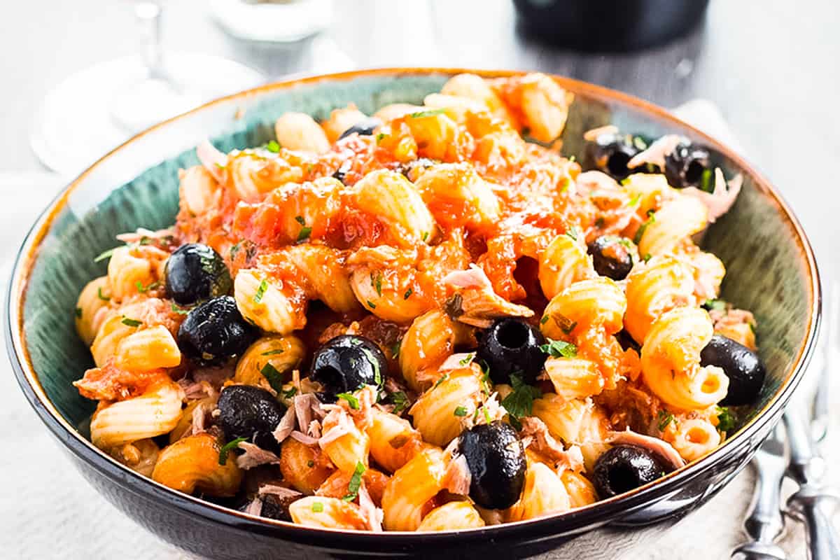 A plate of tuna pasta with olives and tomato sauce