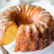 An orange Bundt cake on a glass cake stand.