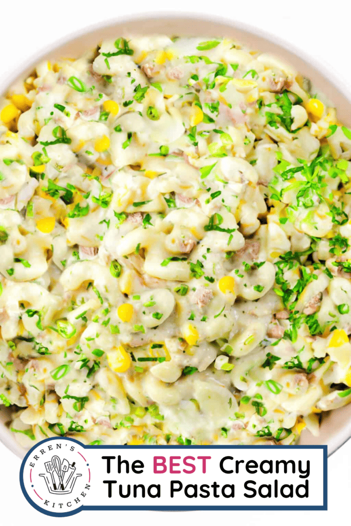 A big bowl of creamy pasta salad with tuna and corn and sprinkled with green onions on top.