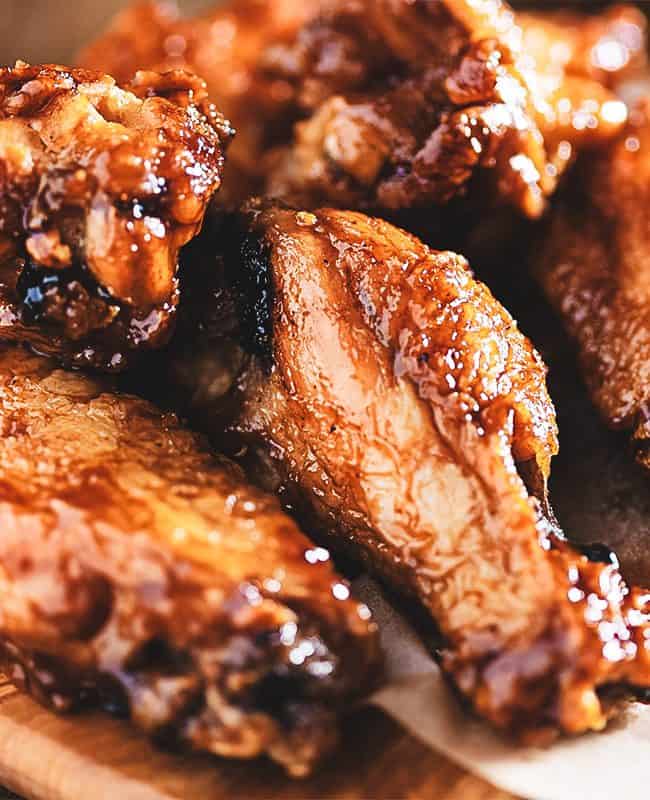 Chicken wings on a wood block with dipping sauce in the background