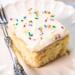 vanilla cake on a plate topped with frosting and sprinkles