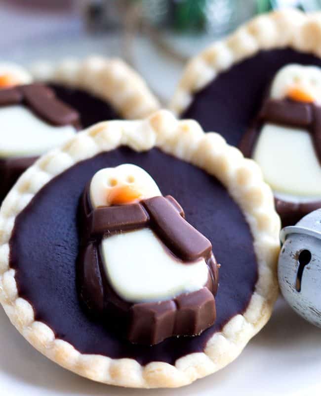 Three chcolate tarts on a plate with christmas decorations