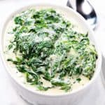 creamed spinach in a dish ready to serve with a spoon beside it