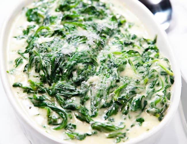 creamed spinach in a dish ready to serve with a spoon beside it